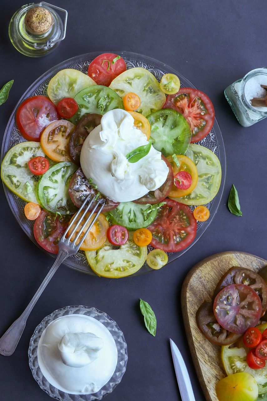 Photo d'illustration : burrata sur des tranches de tomates de couleurs, basilic