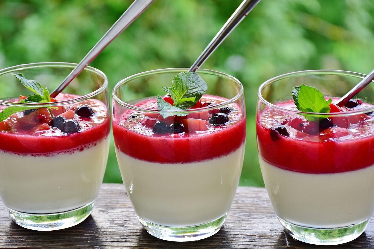 Photo d'illustration : trois verrines de panna cotta nappées de coulis de fruits rouges, menthe